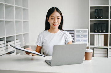 Successful Asian Businesswoman Analyzing Finance on Tablet and Laptop at Office Desk tax, report, accounting, statistics, and analytical research concept.