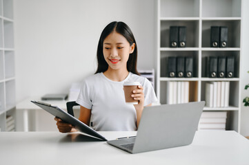 Successful Asian Businesswoman Analyzing Finance on Tablet and Laptop at Office Desk tax, report, accounting, statistics, and analytical research concept.