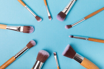 Cosmetic makeup brush on blue background. Cosmetic product for make-up. Creative and beauty fashion concept. Fashion. Collection of cosmetic makeup brushes, top view, banner.Place for text. MOCAP.