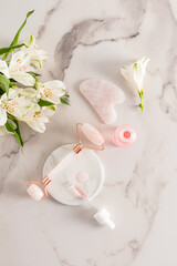 quartz roller massager, gua sha, open matte bottle with a cosmetic product for maasage and face and body skin care. Vertical view.