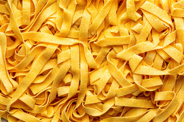 Homemade fresh, uncooked tagliatelle or fettuccine background,  is a traditional type of italian pasta.  Long, flat ribbons traditionally made of egg and flour. Directly above.