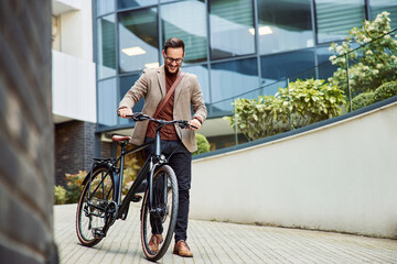 A happy businessman pushing a bicycle in front of the company and going home.