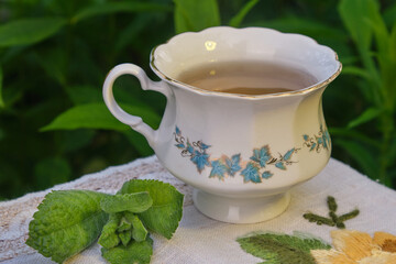 mint tea outdoors in a mug, mint leaves, flowers