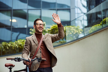 A businessman greeting a colleague in front of the company and pushing a bicycle.