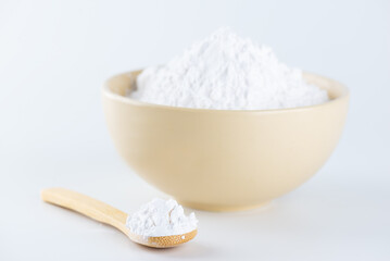 Tapioca starch in a wooden spoon and bowl on a white background.