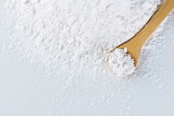 Heap tapioca starch and a wooden spoon, top view, copy space.