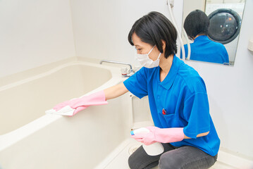 バスルームの清掃をする作業着姿の女性