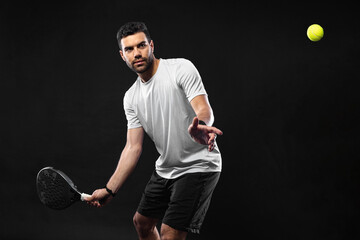 Padel tennis player. Man athlete with paddle tenis racket on black background. Sport concept....
