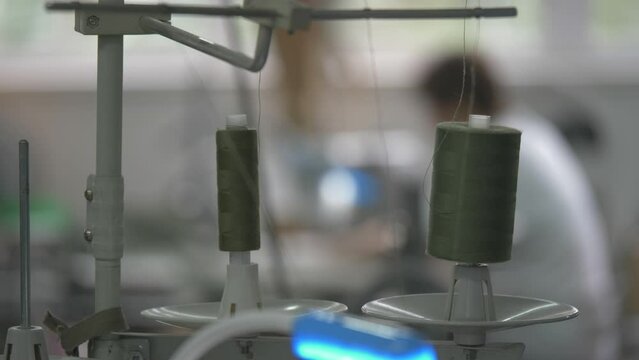 This stock video shows two spools of thread on an industrial sewing machine. This video will decorate your projects related to sewing, sewing machines.