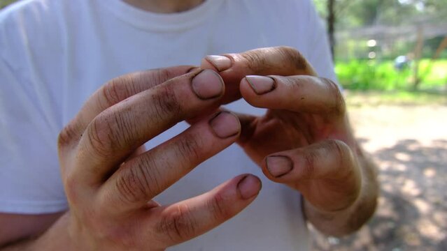 Close up of man showing his dirty hands and nails full of soil after doing some gardening.