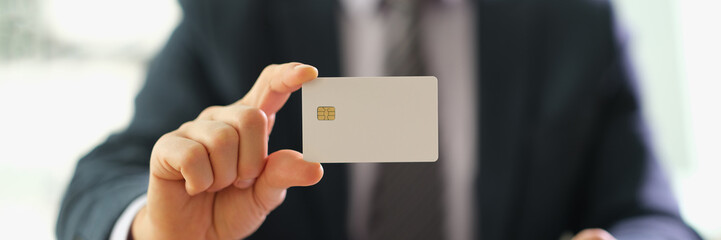 Male manager in suit holding plastic credit card closeup. Payment by cashless payments concept