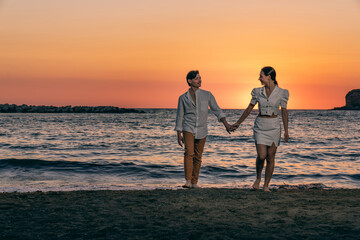 Photoshoot of young helthy beautiful caucasian couple, boy and girl, dating at the beach - Man and woman lovers having fun in holidays walking near the ocean in a sunny day