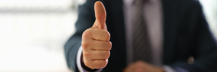 Businessman in suit showing thumbs up on successful deal closeup. Business success concept