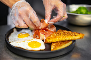 woman chef hand cooking fried eggs with ham