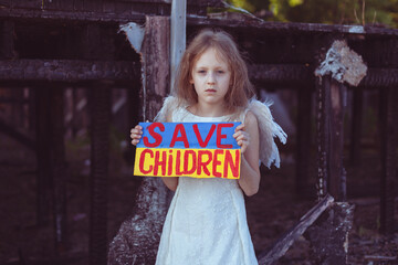 A girl with a poster in her hands asks to protect children. It is against the backdrop of a...