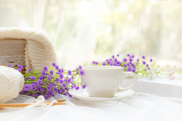 Coffee morning.  White steaming cup of hot coffee for relax after working hobbies crochet on white wooden near window with flowers