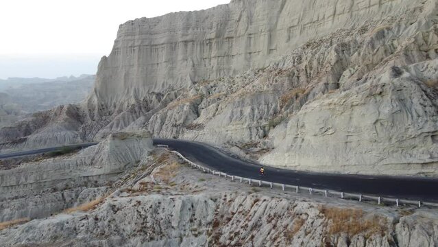 Aerial View Of Cyclist Riding On Remote Road Beside Dramatic Rock Cliff On The Makran Coastal Highway 