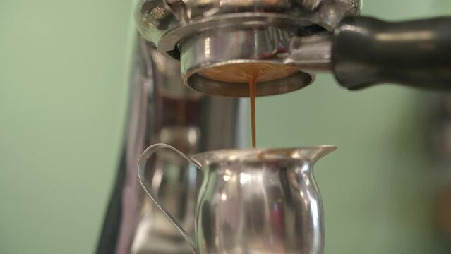 Low angle upward view of coffee dripping through portafilter espresso machine