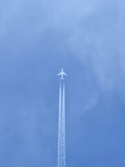 Plane with vapour trails in a blue sky as background