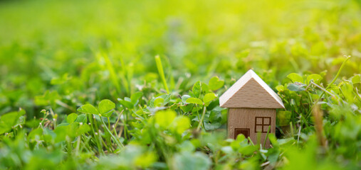 Miniature wooden house on a green grass. Real estate concept. Eco-friendly home. Buying a housing outside the city. Selective focus