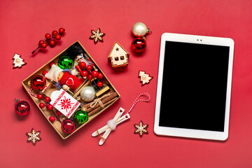 top view tablet with black digital screen, Christmas box and decor on red table Flat lay Holiday shopping list, Happy New Year, online shop, chooses gifts, makes purchases Mockup - 617008322
