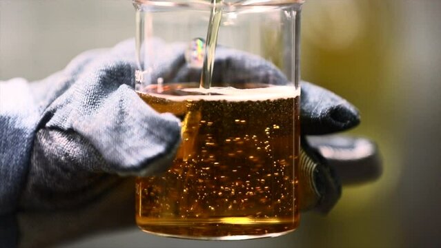 The scientist dropping the chemical solution in beaker in the laboratory experiment. Chemical and Oil concept