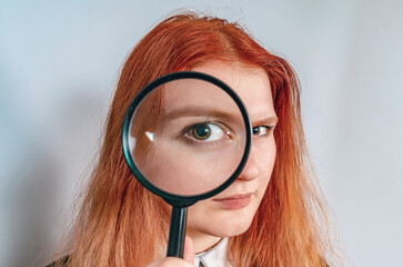 Magnifying glass. A woman's face through a magnifying glass. Big eyes. Research, choice concept.