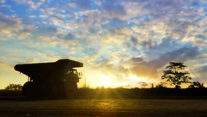 A silhouette of a mining truck crosses the hauling road under a beautiful morning sky, adorned by a charming sunrise