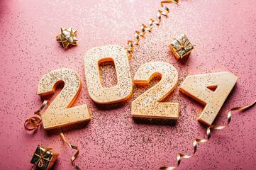 Happy New Year 2024. Golden digits 2024 with glitter and xmas decorations nearby. Holiday Party Decoration or postcard concept with top view and copy space.