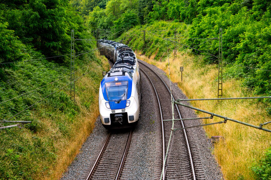 German regional train in a curve of the main railway line between cologne and Berlin near Dortmund on a summer day with yellow grass and green forest. Multiple unit on its way to next stop Unna.