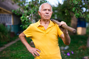 Naklejka na ściany i meble Portrait of mature farmer with shovel on garden
