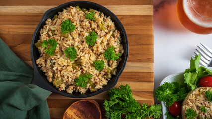 Dirty rice, a classic cajun dish made with ground pork, celery, onions, garlic scapes, and green pepper. Topped with parsley.