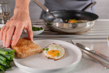 Making breakfast. Woman is serving fresh toast on a plate with fried egg