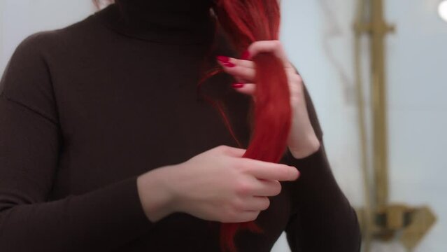 A woman brushing her red hair using her hands 