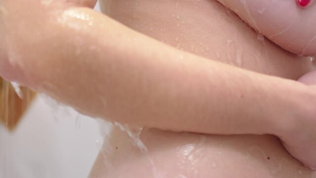 Naked sexy woman taking cold shower, close up view of nude body