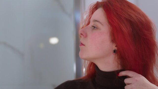 An attractive young woman brushing her red hair