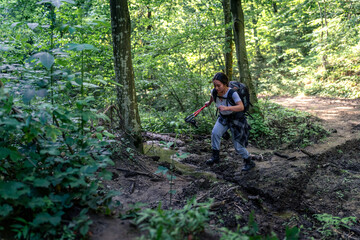 a young mountaineer walks through the forest and crosses a shallow stream