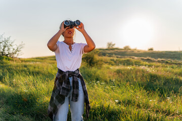 A young adventurer uses binoculars as she walks through the fields and watches birds