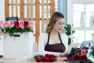 Beautiful asian woman florist working in flower shop.