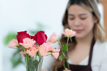 Beautiful asian woman florist holding bouquet of roses in flower shop.