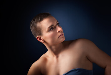 Naklejka premium portrait of young woman with short hair and bare shoulder on blue bakground