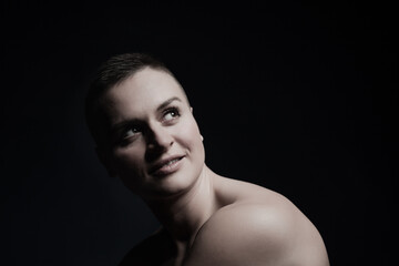 portrait of young woman with short hair and bare shoulder on black bakground