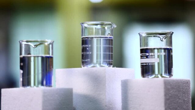 A close up of Multiple beakers in a lab, and contains chemical or liquid.
