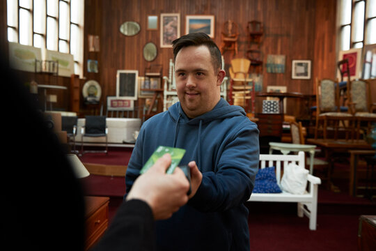 Worker with Down syndrome serving client in furniture store