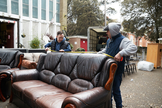 Male workers measuring leather sofa