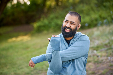 Smiling young man stretching in park
