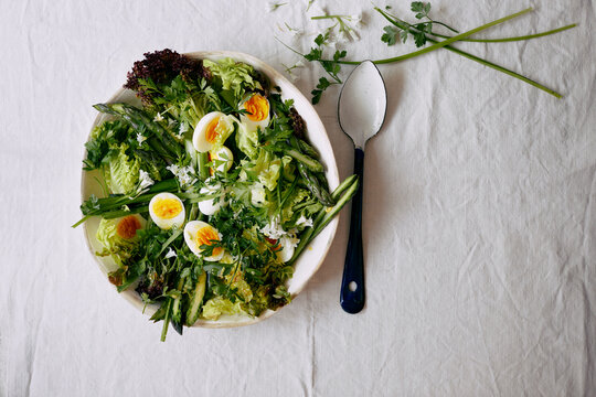 Overhead view of salad with eggs, asparagus and herbs