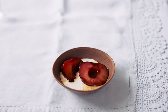 Caramelized plums with double cream in bowl