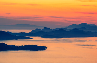 An incredible aerial view of the islands in the water area of the city of Dubrovnik at a fiery sunset.