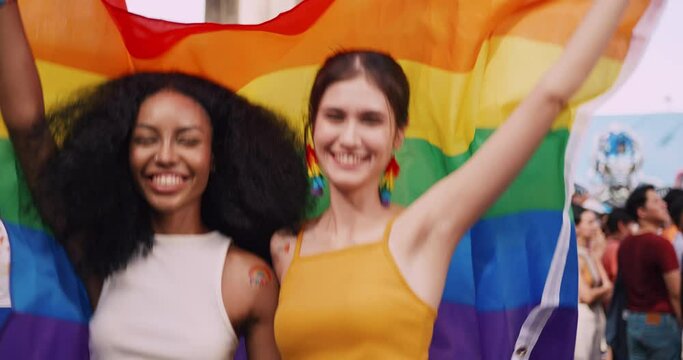 A lesbian couple with a rainbow tattoo sticker and flag representing the symbol of homosexuality in a pride parade.